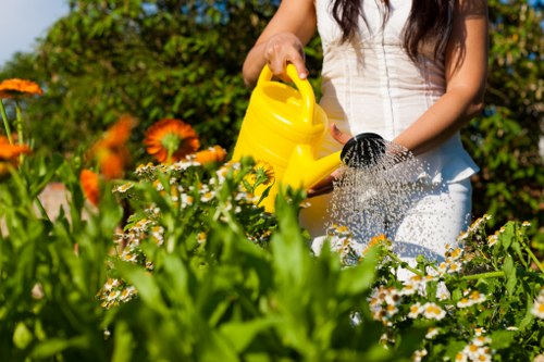 Operative wearing PPE: hi-vis, gloves, ear protection while mowing a lawn